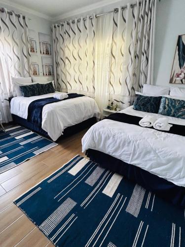 a bedroom with two beds and a blue rug at Hope Villa Luxury Accomodation in Odendaalsrus