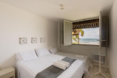 a bedroom with a bed and a window with the ocean at Cohost Casa Pedra do Anel in Vila Velha