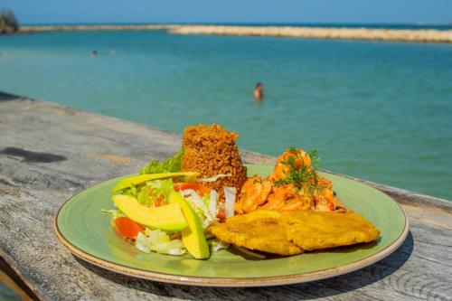 a green plate of food on a table near the water at Ecohotel Nativa Beach in Cartagena de Indias