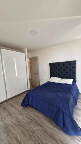 ein Schlafzimmer mit einem großen Bett mit einer blauen Decke in der Unterkunft Departamento en Angelópolis in El Gallinero