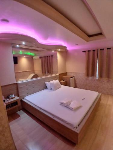 a bedroom with a large bed with pink lighting at Motel Encontros in Poá