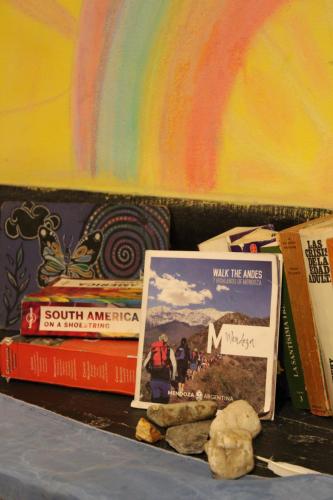 a pile of books sitting on a table with a rainbow in the background at The Grapevine Hostel in Mendoza