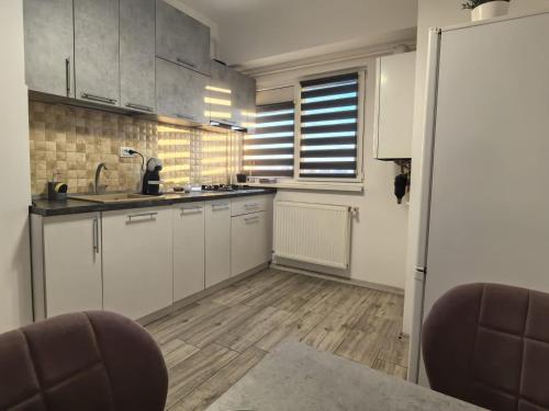 a kitchen with white cabinets and a wooden floor at Quantum Apartament 22 in Craiova