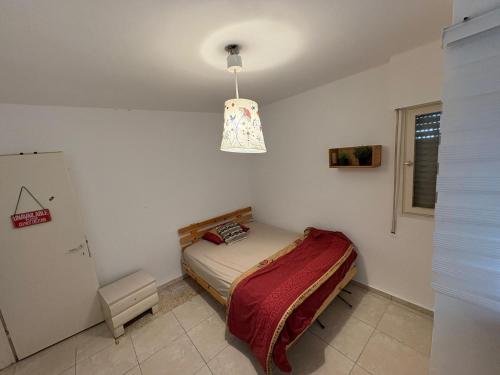 a small bedroom with a bed and a hanging light at חניתה 40 חיפה in Haifa