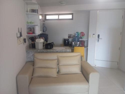 a living room with a couch and a kitchen at Flat beiramar praia de Tabatinga in Conde