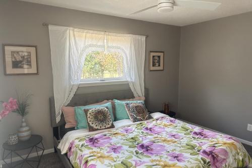 a bedroom with a bed with a floral comforter and a window at Modern Lux 3BR King Bed in Copperas Cove