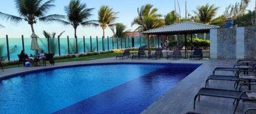 a large swimming pool with chairs and a gazebo at Flat beiramar praia de Tabatinga in Conde