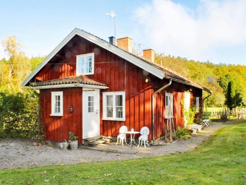 a red house with two chairs and a table at 8 person holiday home in Vargön in Västra Tunhem