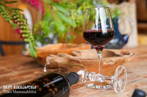 a glass of wine next to a bottle of wine at Niko Mamasakhlisi Guest House in Ozurgetʼi