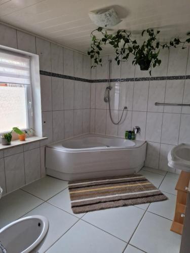 a white bathroom with a tub and a sink at Ferienwohnung Krysanovsk in Eslarn