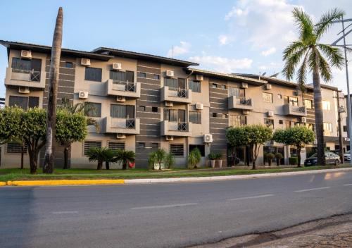 a large apartment building with palm trees and a street at FLORENÇA PALACE HOTEL in Lucas do Rio Verde