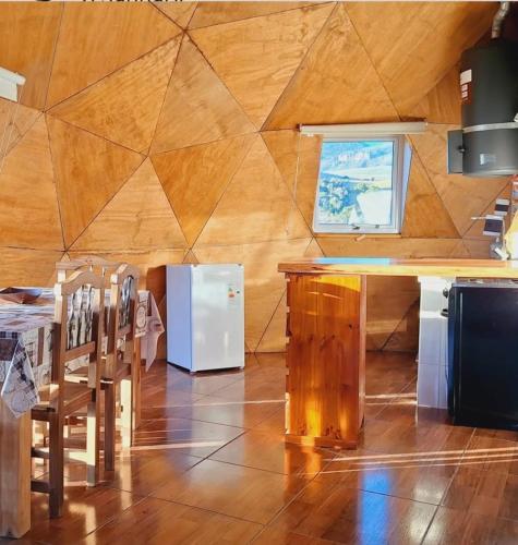 a kitchen with a wooden wall with a table and chairs at Domo Kumelén Mahuida in Junín de los Andes