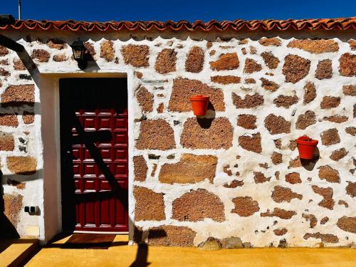 un edificio con puerta roja y pared de piedra en Las Casitas - Casa Higo, en Granadilla de Abona