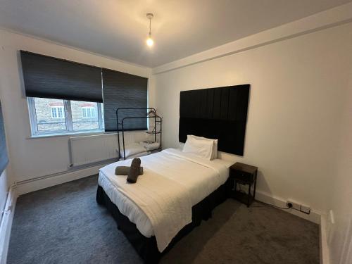 a bedroom with a bed with a black headboard and a window at 2 Bedroom flat by London Bridge & The Shard in London