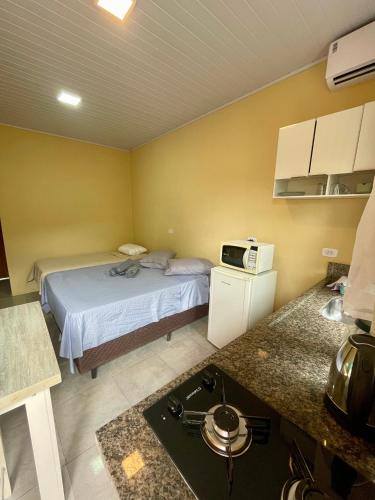 a small room with a bed and a microwave at Mini Casa 5 in Itajaí