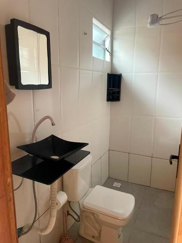 a bathroom with a toilet and a sink and a mirror at Mini Casa 5 in Itajaí