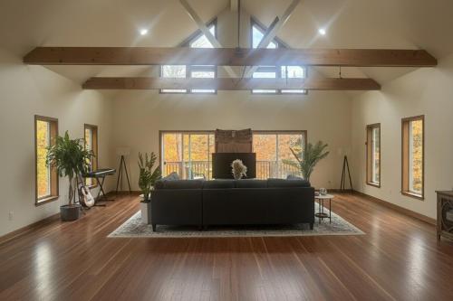 a living room with a black couch in the middle at Blue Bird Chalet 5BR with Sauna near Skiing in East Chatham
