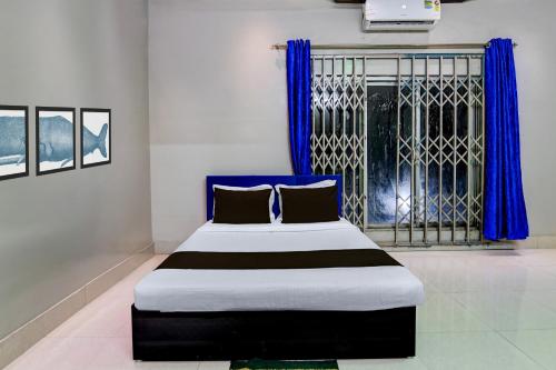 a bedroom with a large bed with blue curtains at Hotel O Green Eco Space in Devanandapur
