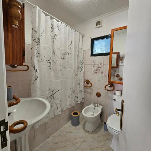a bathroom with a sink and a toilet and a shower curtain at JoLi Larano - 3 Bedrooms & 2 WC Exclusive in Machico