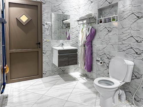 a white bathroom with a toilet and a sink at Hotel America Apartments in Dakhla