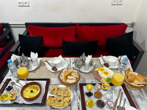 a table with breakfast food on it with a red couch at Hotel America Apartments in Dakhla