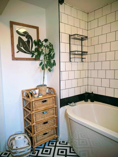 La salle de bains est pourvue d'une baignoire et d'une plante en pot. dans l'établissement Stylish home, 3 bed with garden, Fast WiFi Parking, à Peterborough
