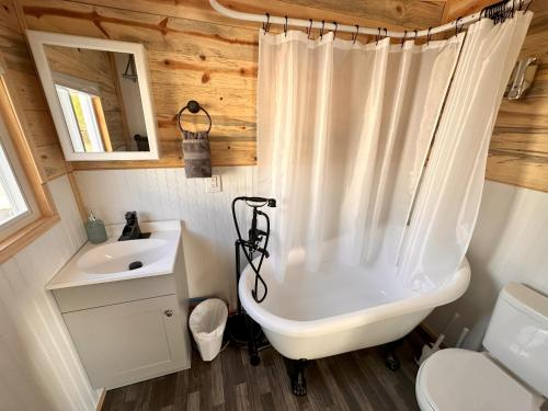 a bathroom with a tub and a sink and a toilet at Enchanting Getaway Farmhouse And Tiny House Duo in Jacksonville