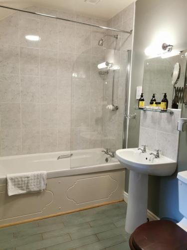 a bathroom with a tub and a sink and a shower at Kilmokea Coach House in New Ross