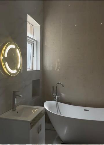 a bathroom with a white tub and a sink at The Manor in Ikoyi