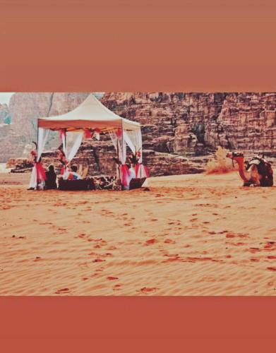 Un grupo de personas sentadas bajo una tienda de campaña en el desierto. en وادي رم, en Wadi Rum