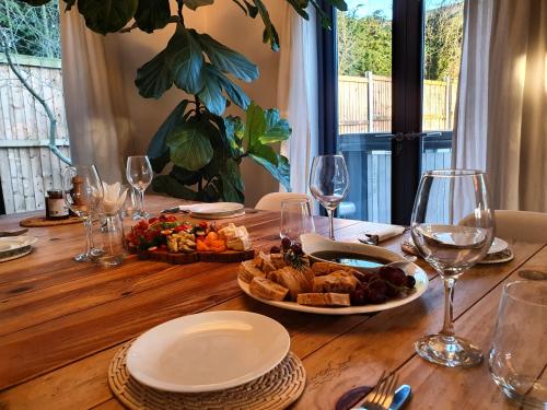 a wooden table with a plate of food and wine glasses at Island Retreat with HotTub in West Mersea