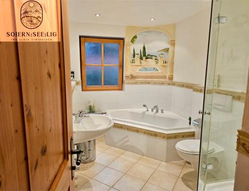 a bathroom with a tub and a sink and a toilet at Ferienwohnung Soiernseelig in Wallgau