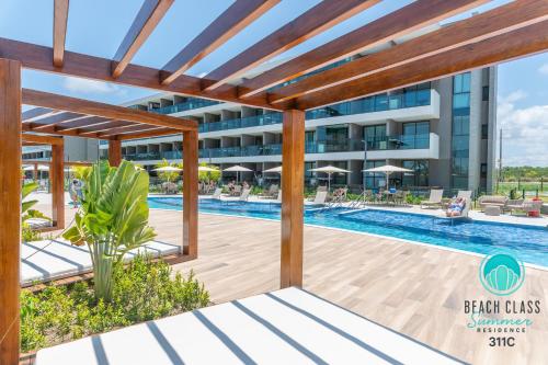 Refúgio Verão - Flat de alto padrão na praia do Cupe - Porto de Galinhas في بورتو دي غالينهاس: صورة للجزء الخلفي من المنتجع مع حمام سباحة