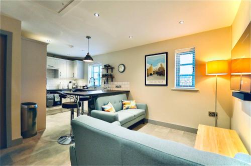 a living room with a couch and a kitchen at Luxury Two Bed Suite - Walk to Trentham Gardens! in Stoke on Trent
