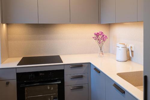 a kitchen with white cabinets and a vase of flowers at Vytauto 12 in Marijampolė
