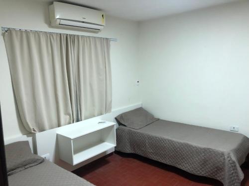 una piccola stanza con due letti e una finestra di Casa para Estadia a Foz do Iguaçu