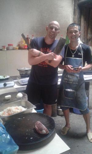 two men standing in a kitchen holding large knives at Tavan View Homestay in Sa Pa