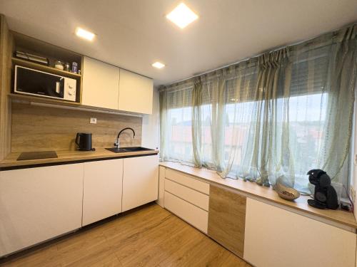 eine Küche mit weißen Schränken und einem großen Fenster in der Unterkunft Dreams Apartment Bacvice in Split