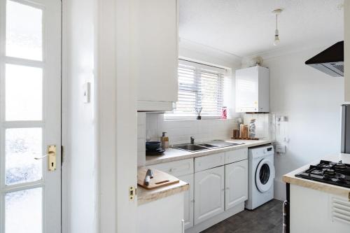 a white kitchen with a sink and a stove at Cosy 2-Bed Maisonette in Ashford in Kennington