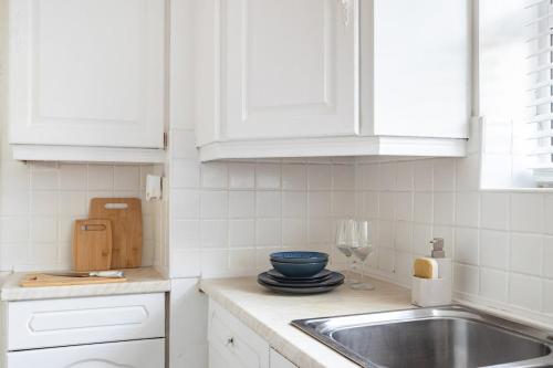 eine Küche mit weißen Schränken und einer Spüle in der Unterkunft Cosy 2-Bed Maisonette in Ashford in Kennington