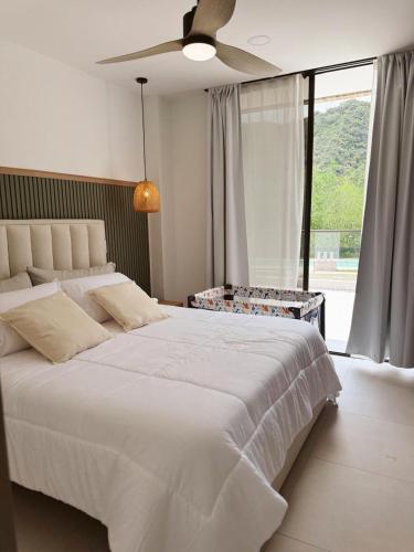 a bedroom with a large white bed with a ceiling fan at KOA Villeta - Loft y terraza con vista a la montaña in Nimaima