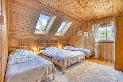twee bedden in een kamer met houten wanden en ramen bij Domki Letniskowe Jerutki in Świętajno