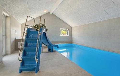an indoor swimming pool with a blue slide in a house at Awesome Home In Glesborg With Sauna in Fjellerup