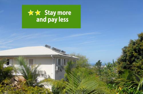a house with a green sign that says stay more and pay less at Les Hibiscus de la Rivière in Saint-Louis