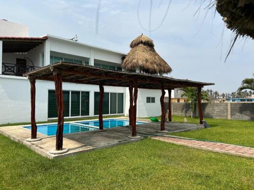 ein Pavillon mit Dach neben einem Haus in der Unterkunft Beautiful Beach House in Barra de Coyuca