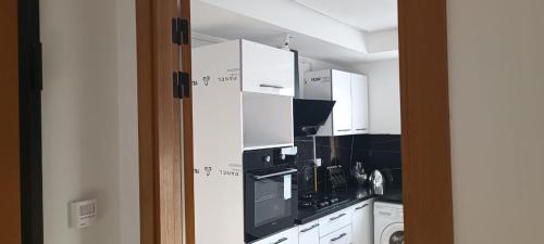 a kitchen with white cabinets and black appliances at Fatimides 2 in El Aouina Station