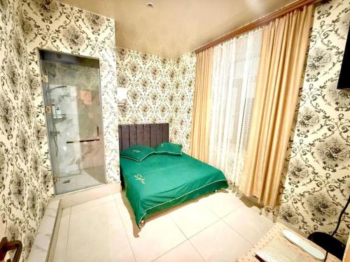 Un dormitorio con una cama verde en una habitación con papel pintado en Hostel, en Ereván