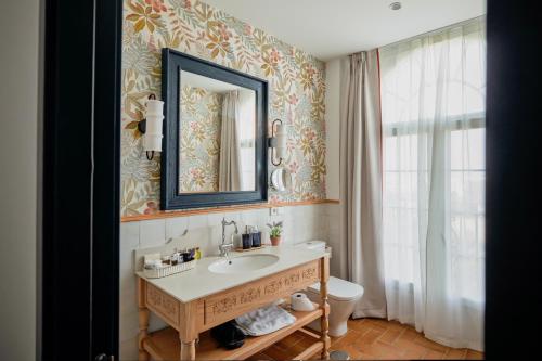 Un baño con lavabo, espejo e inodoro. en Hotel Toruño del Rocío, en El Rocío