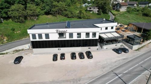 a white building with cars parked in a parking lot at Prenoćište Vozač in Jajce