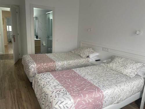 Un dormitorio con dos camas y un espejo. en La mesa del cocinero, en Lugo